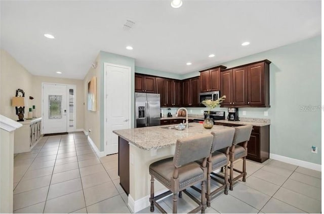 kitchen featuring recessed lighting, light tile patterned floors, a breakfast bar, a sink, and appliances with stainless steel finishes