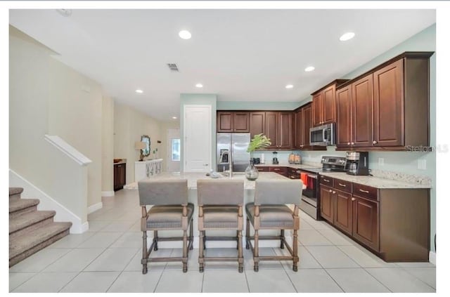kitchen with a kitchen bar, recessed lighting, light tile patterned floors, stainless steel appliances, and visible vents