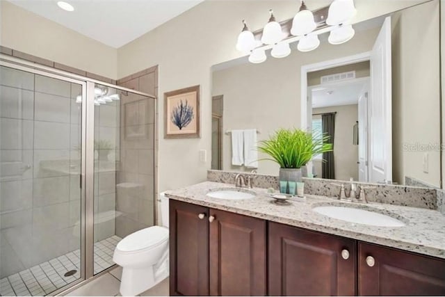 full bath featuring a stall shower, double vanity, toilet, and a sink