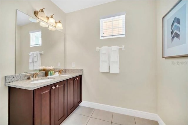 bathroom featuring baseboards, double vanity, a sink, and tile patterned flooring