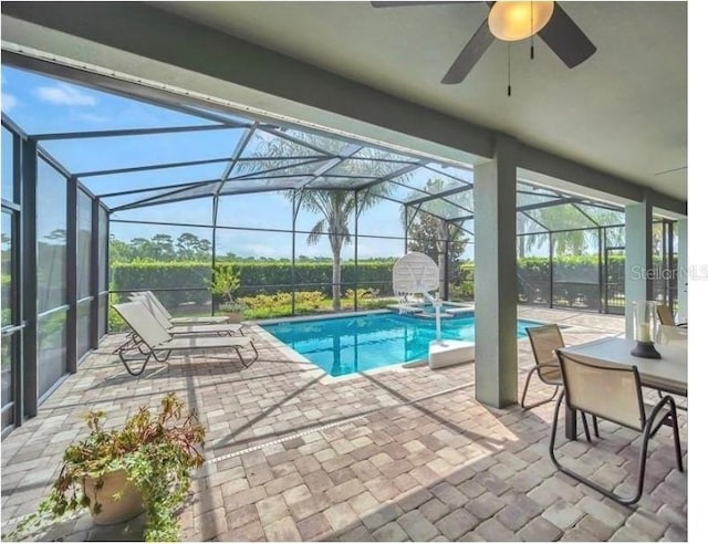 view of swimming pool featuring glass enclosure, ceiling fan, a pool with connected hot tub, and a patio area