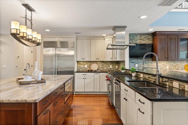 7849 Georgeann St, Winter Park, FL 32792 - kitchen with island range hood, a sink, built in appliances, wood finished floors, and tasteful backsplash