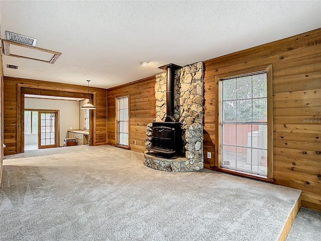 410 Sandspur Rd N, Maitland, FL 32751 - unfurnished living room featuring carpet floors, visible vents, wood walls, and a wood stove
