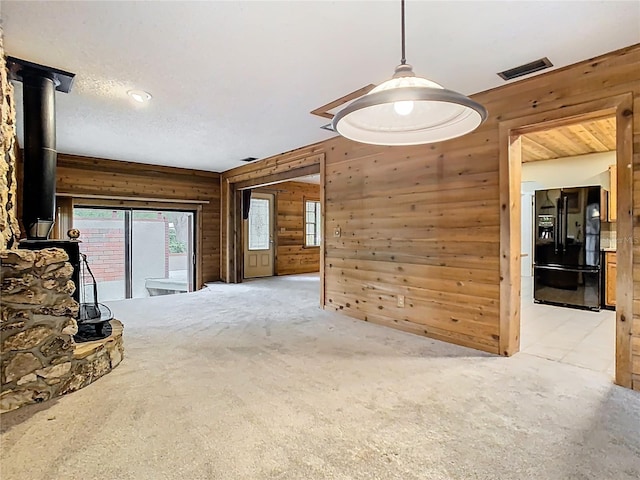 410 Sandspur Rd N, Maitland, FL 32751 - unfurnished living room with carpet floors, visible vents, wooden walls, and a wood stove