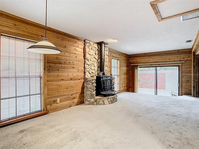 410 Sandspur Rd N, Maitland, FL 32751 - unfurnished living room featuring visible vents, wood walls, carpet, and a wood stove