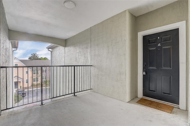 view of exterior entry featuring a balcony and stucco siding