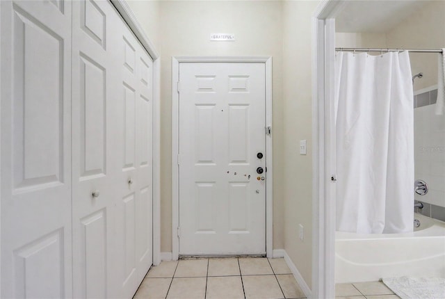 doorway with light tile patterned flooring and baseboards