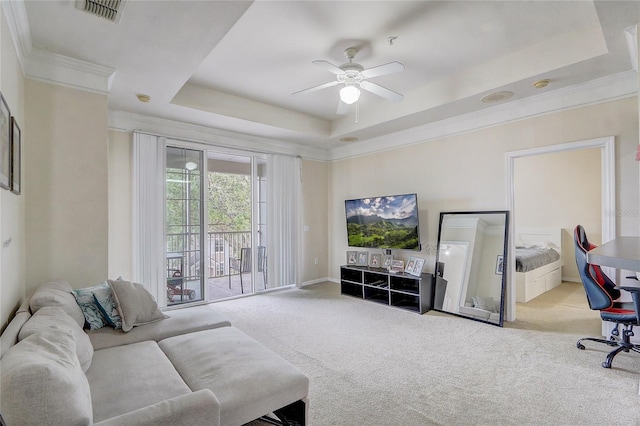 living area with a tray ceiling, carpet floors, and a ceiling fan