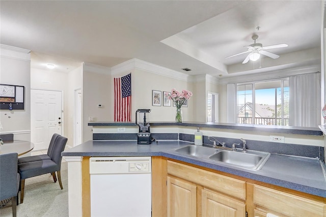 kitchen with light brown cabinets, dark countertops, a sink, and white dishwasher
