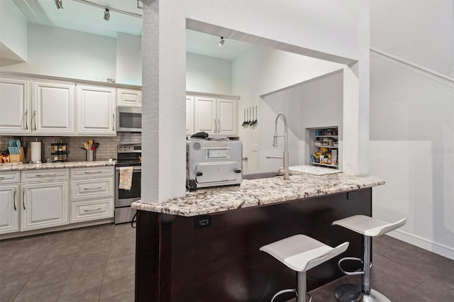 10724 Harkwood Blvd, Orlando, FL 32817 - kitchen with tasteful backsplash, white cabinets, a sink, and stainless steel appliances