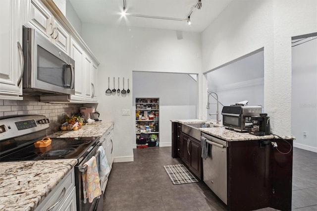 10724 Harkwood Blvd, Orlando, FL 32817 - kitchen with light stone counters, white cabinets, decorative backsplash, stainless steel appliances, and a sink