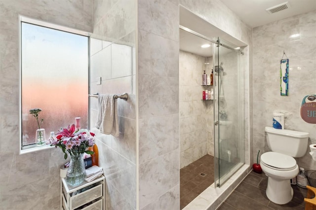 10724 Harkwood Blvd, Orlando, FL 32817 - bathroom with a shower stall, tile patterned flooring, visible vents, toilet, and tile walls