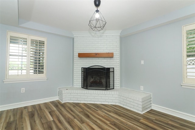 unfurnished living room with a brick fireplace, baseboards, and wood finished floors