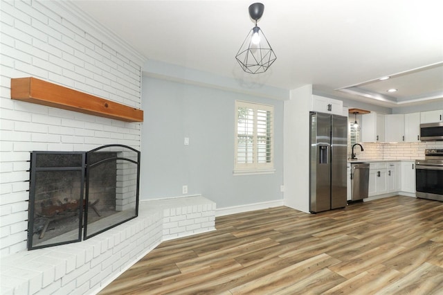 kitchen featuring white cabinets, a sink, light countertops, appliances with stainless steel finishes, and light wood finished floors