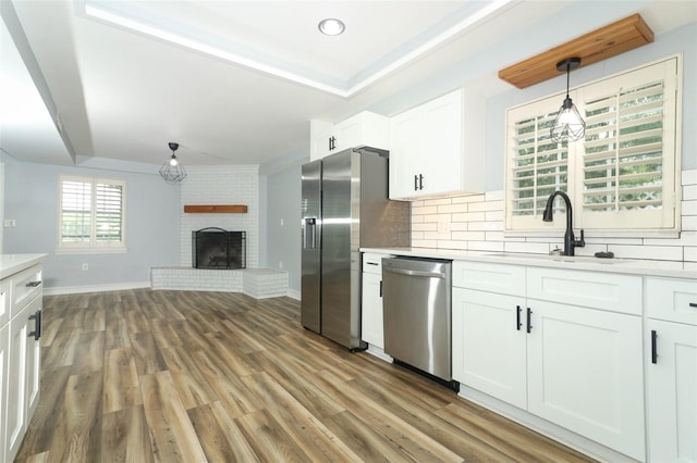 kitchen featuring white cabinetry, appliances with stainless steel finishes, light countertops, a sink, and decorative backsplash