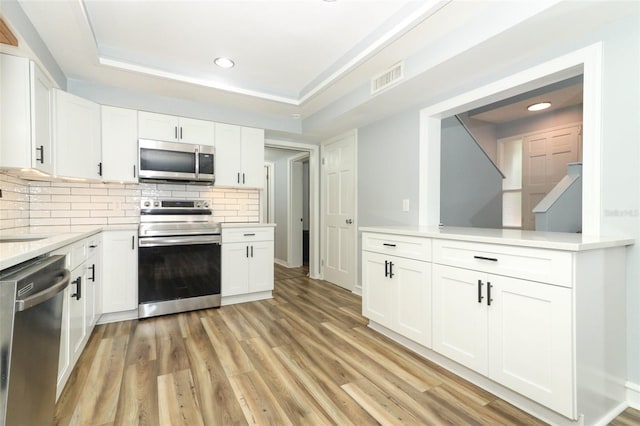 kitchen featuring recessed lighting, light countertops, backsplash, white cabinetry, and appliances with stainless steel finishes