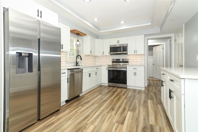 kitchen with light wood-type flooring, white cabinetry, light countertops, a sink, and stainless steel appliances