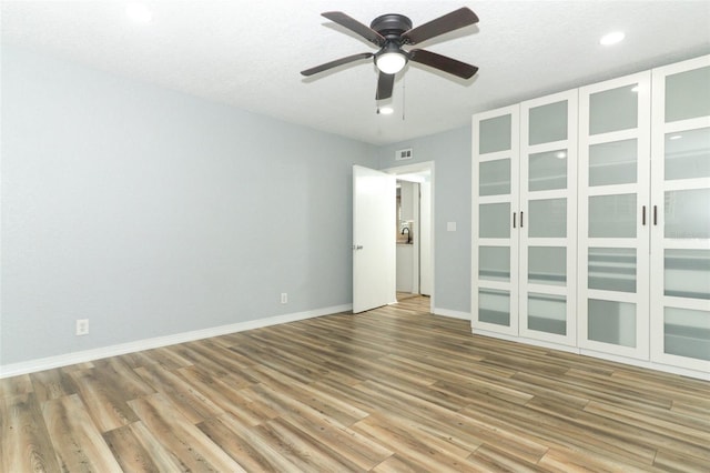unfurnished room featuring baseboards, recessed lighting, a ceiling fan, visible vents, and wood finished floors
