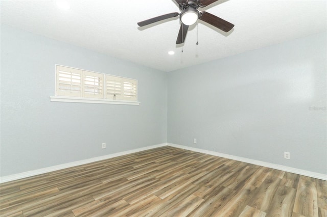 empty room with wood finished floors, ceiling fan, baseboards, and recessed lighting