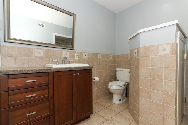 bathroom featuring vanity, a wainscoted wall, toilet, visible vents, and tile walls