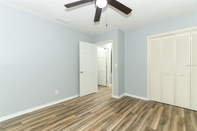 unfurnished bedroom with visible vents, a closet, baseboards, a ceiling fan, and wood finished floors