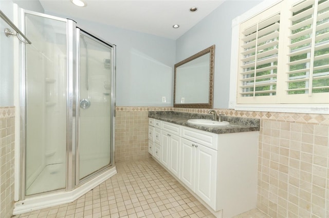 bathroom featuring tile patterned floors, tile walls, a shower stall, and a wainscoted wall