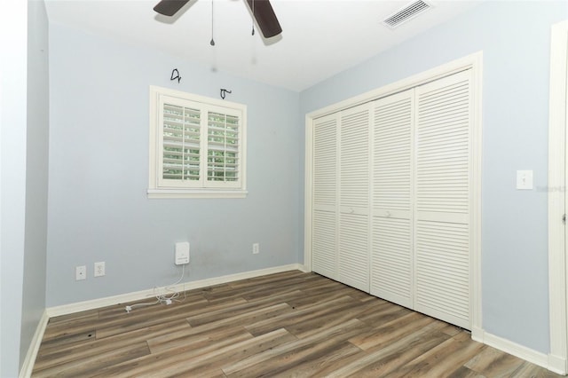 unfurnished bedroom featuring a closet, a ceiling fan, visible vents, wood finished floors, and baseboards