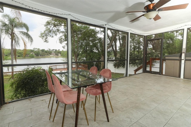 sunroom featuring ceiling fan and a water view