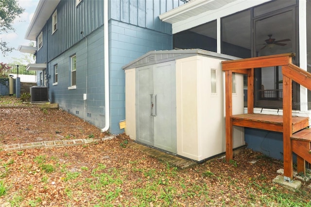view of side of property featuring central AC unit, a storage shed, board and batten siding, and an outbuilding