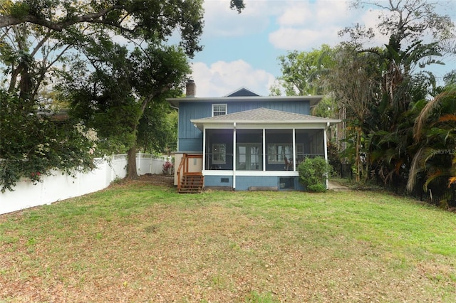 rear view of property featuring a fenced backyard, a chimney, a sunroom, and a lawn