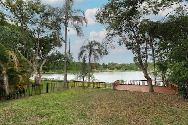 view of yard featuring a deck with water view and fence