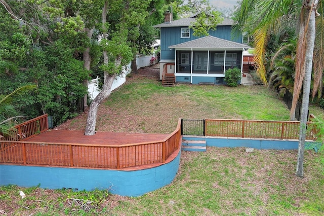 view of yard featuring fence, a wooden deck, and a sunroom