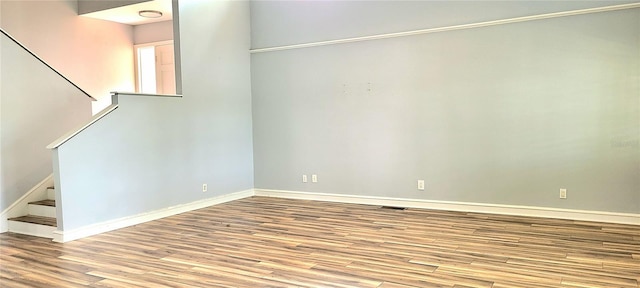 spare room with wood finished floors, baseboards, and stairs