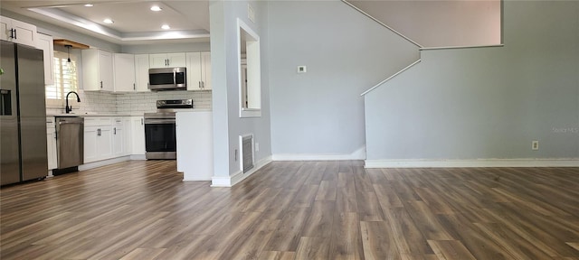 kitchen with dark wood-style flooring, backsplash, visible vents, a tray ceiling, and stainless steel appliances