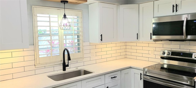 kitchen featuring light countertops, appliances with stainless steel finishes, a sink, and white cabinets