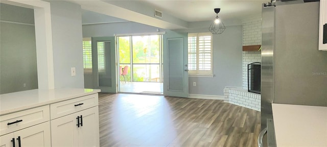 interior space with a brick fireplace, visible vents, baseboards, and dark wood-style floors