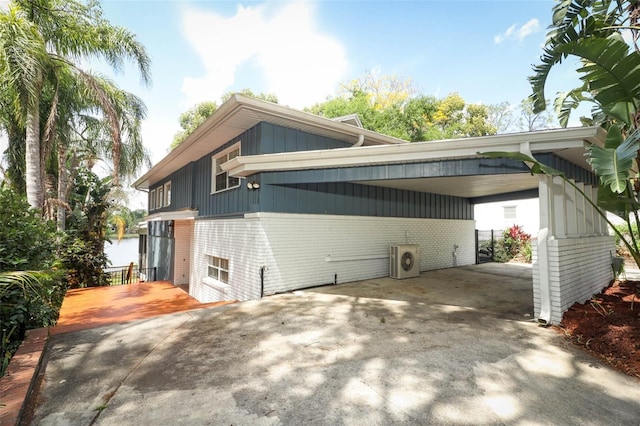 view of property exterior featuring brick siding, a carport, and driveway