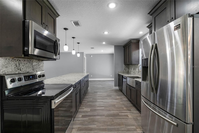 607 Wavecrest Dr, Orlando, FL 32807 - kitchen with stainless steel appliances, a textured ceiling, backsplash, visible vents, and light stone countertops