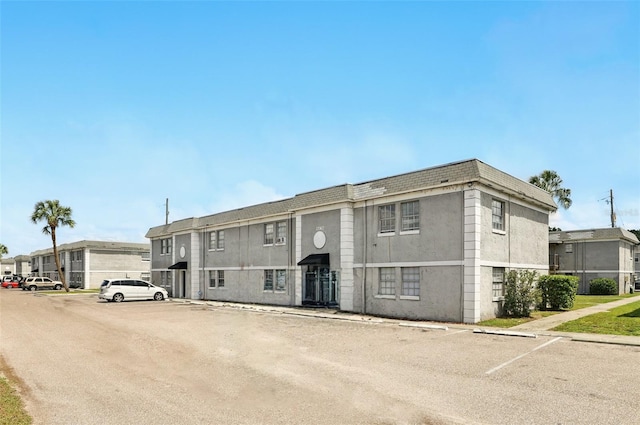 townhome / multi-family property with stucco siding and uncovered parking