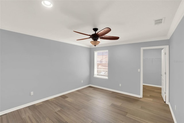 empty room featuring crown molding, visible vents, baseboards, and a ceiling fan