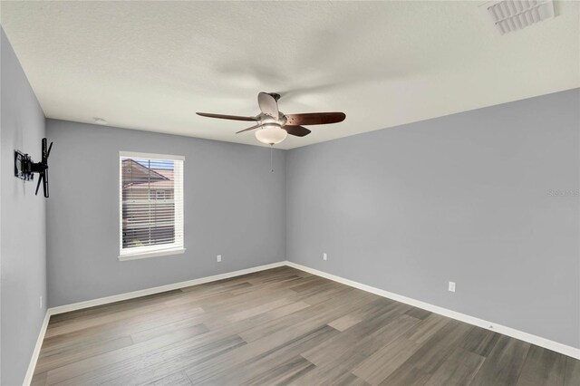 empty room featuring visible vents, ceiling fan, wood finished floors, and baseboards