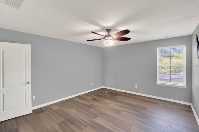 spare room featuring visible vents, ceiling fan, baseboards, and wood finished floors