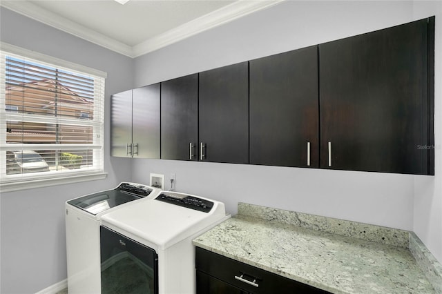 clothes washing area featuring crown molding, a healthy amount of sunlight, washing machine and dryer, and cabinet space