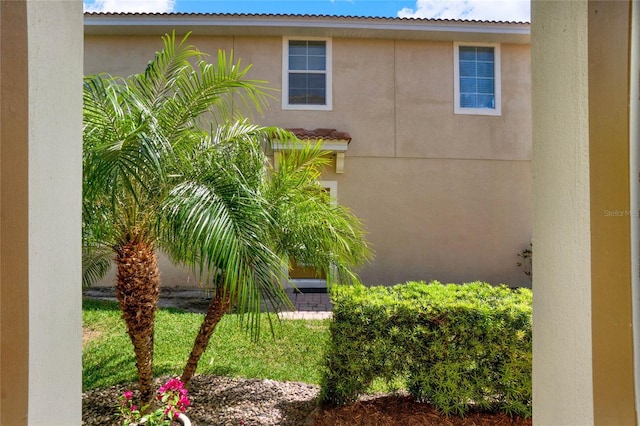 view of side of property with stucco siding and a tile roof