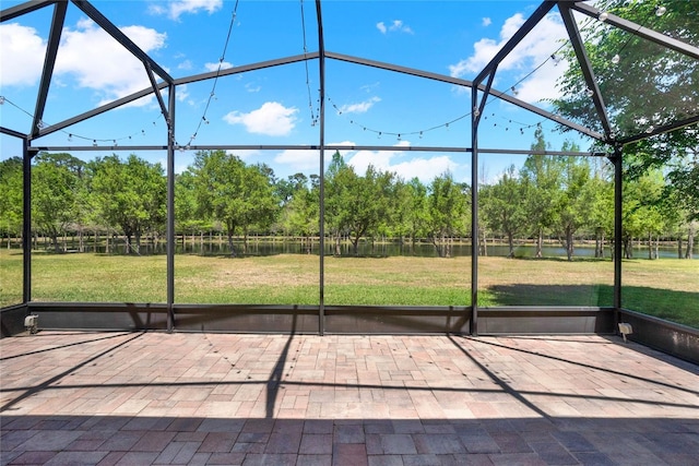 view of patio featuring glass enclosure and a water view