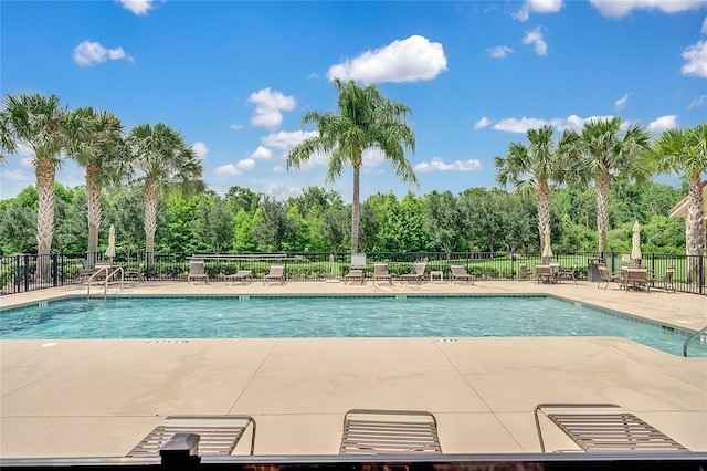 pool with a patio area and fence