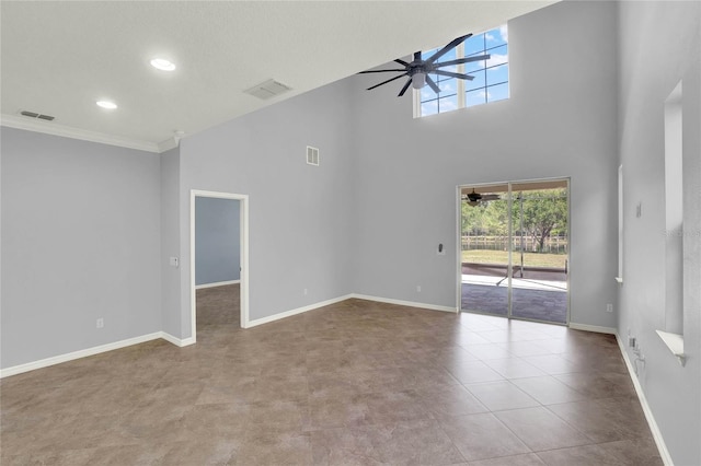 empty room featuring visible vents, ceiling fan, a towering ceiling, and baseboards