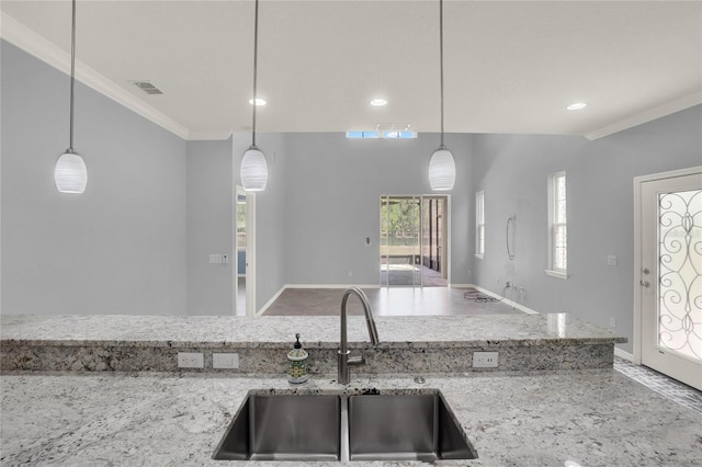 kitchen featuring crown molding, recessed lighting, light stone counters, a sink, and hanging light fixtures