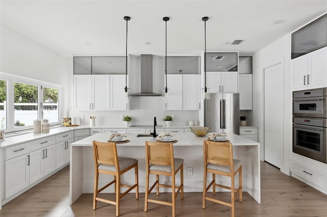 2408 Lafayette Ave, Winter Park, FL 32789 - kitchen featuring visible vents, light wood-style flooring, a kitchen bar, stainless steel appliances, and wall chimney exhaust hood