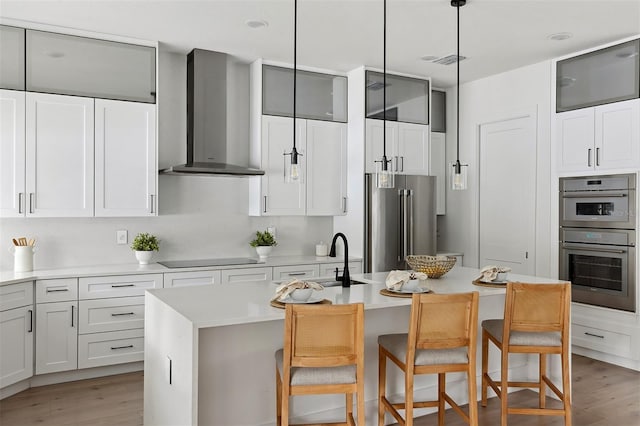2408 Lafayette Ave, Winter Park, FL 32789 - kitchen with visible vents, a kitchen bar, a center island with sink, appliances with stainless steel finishes, and wall chimney range hood
